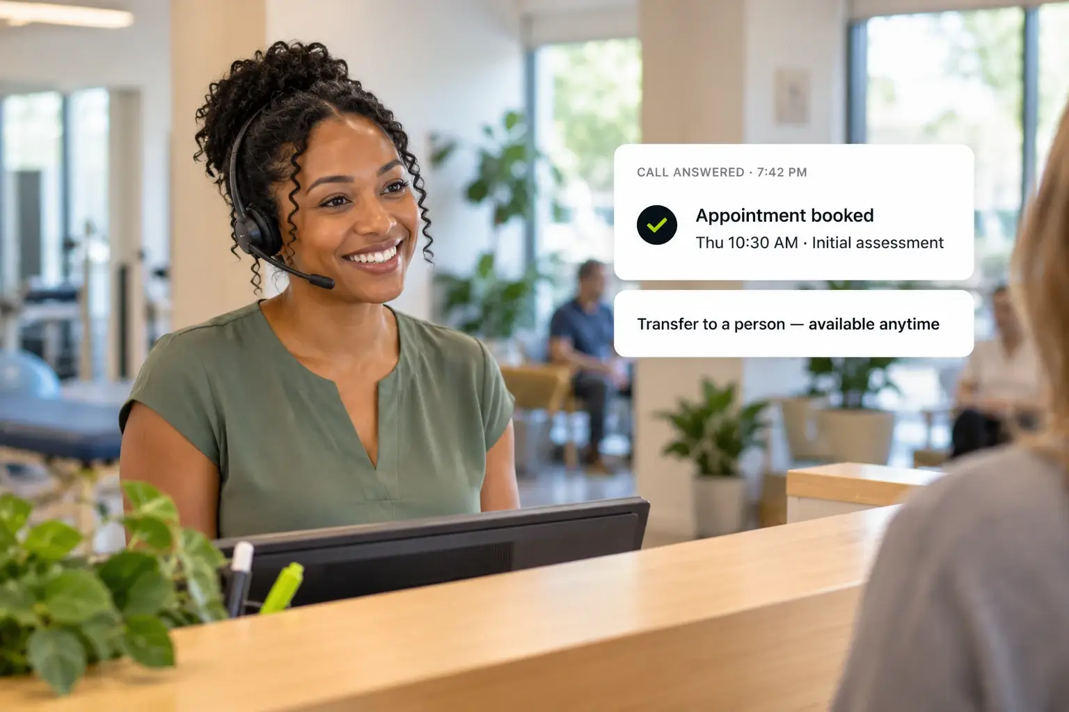 A smiling front-desk lead in a headset greets a patient at a clinic reception counter while an after-hours call is answered and an appointment is booked for Thursday at 10:30 AM, with transfer to a person available anytime.
